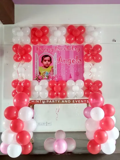 A simple balloon frame decoration for a kid's birthday at home. The red and white balloon columns and arch frame a personalized photo banner.