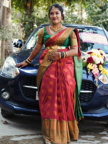 A confident bride-to-be posing on her engagement day. She wears a traditional red and green silk saree, and her makeup is classic and timeless.