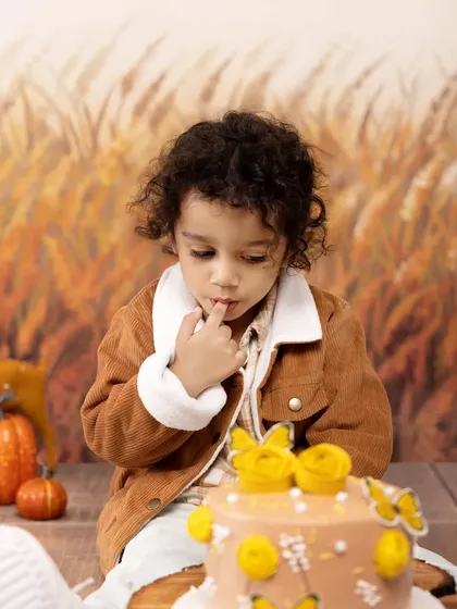 The moment of sweet anticipation right before the smash. This little one is mesmerized by his beautiful birthday cake in our autumn-themed studio setup.