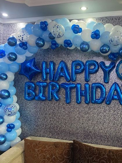 A classic 'Happy Birthday' decoration with a blue and white balloon arch and large blue foil letters, perfect for any age.