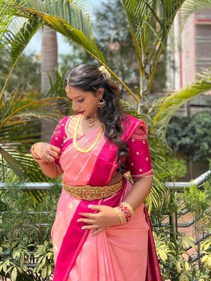 A three-quarter view of the client in her pink saree, showing the detail on the puffed sleeves of her custom blouse.