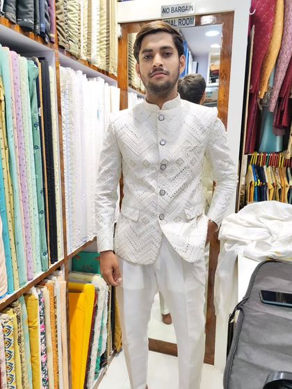 A client trying on his white Jodhpuri suit with mirror work. The fit is tailored to be comfortable while maintaining a sharp silhouette.
