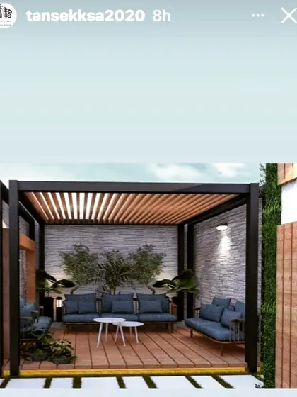A compact and stylish pergola with a metal frame and a wooden slat roof. The design includes a stone-textured back wall and is furnished with modern blue sofas, perfect for a small patio.