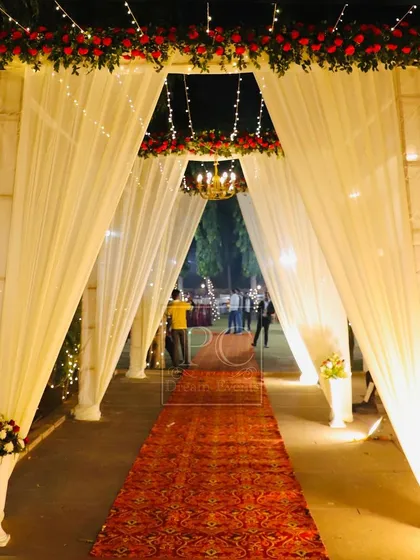 A view from inside the entrance tunnel, looking towards the main event area. The red carpet and warm lighting create an inviting and celebratory path for guests.