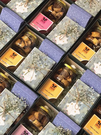 A close-up of the contents within the wedding invite hampers, showing the different colored candles and delicate packaging details.