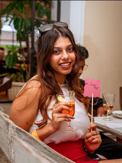 A guest holds up a sign and a drink, fully embracing the fun and festive atmosphere of our event.