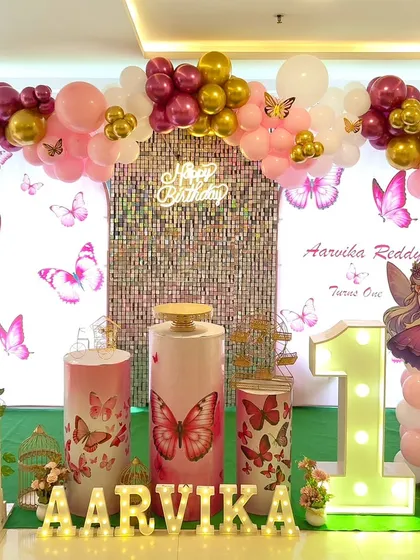 A butterfly-themed first birthday with a pink and gold color scheme. The setup includes a large marquee number '1' and a cute fairy cutout.