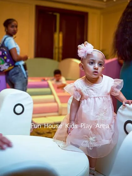 A candid moment of a toddler exploring our white soft play merry-go-round. The equipment is low to the ground and made from soft materials, ensuring a safe environment for the littlest guests.