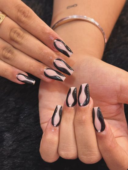 A modern and graphic abstract design. I used a sheer nude base and added bold, flowing black shapes on coffin-shaped nails for a look that is both simple and striking.