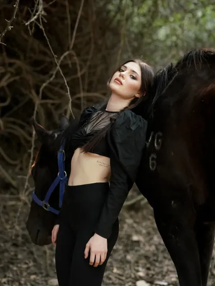 A model leans against a horse, showcasing a relaxed yet confident pose. The natural setting and the bond with the animal are central themes in many shoots here.
