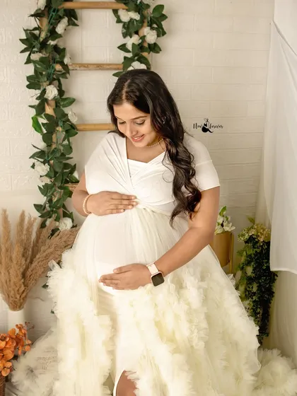 A quiet moment of connection, just you and your baby. I love this pose, with hands cradling the belly, against a soft, floral-themed backdrop in my studio.