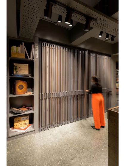 The sliding display system allows for an organized and interactive way to browse through hundreds of material samples. The industrial aesthetic of the showroom is softened by the warmth of the wood.