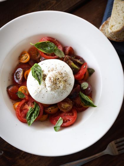 A fresh and simple Caprese salad with creamy burrata, ripe tomatoes, and basil. Highlighting the beauty of quality ingredients.