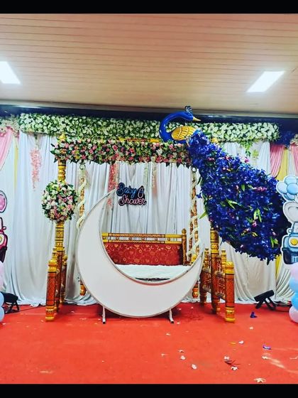 The peacock-themed decor in natural light, showing the contrast between the pink curtain backdrop and the blue floral peacock.