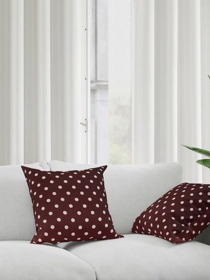 The maroon polka-dot cushions styled on a white sofa, showing how they can add a pop of color to a living room.