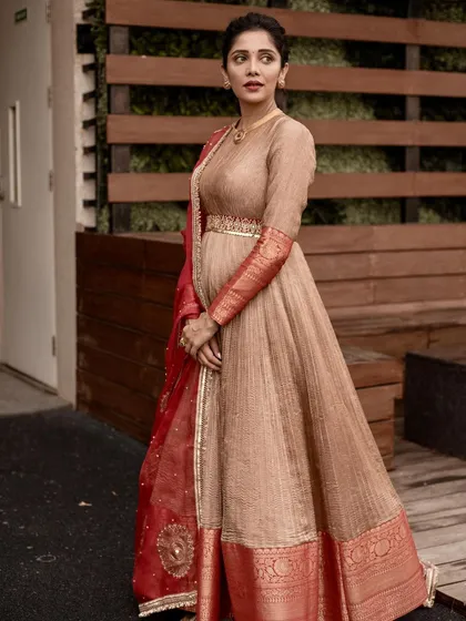 The full view of the beige Anarkali, highlighting its flowing silhouette and the rich red Banarasi border.