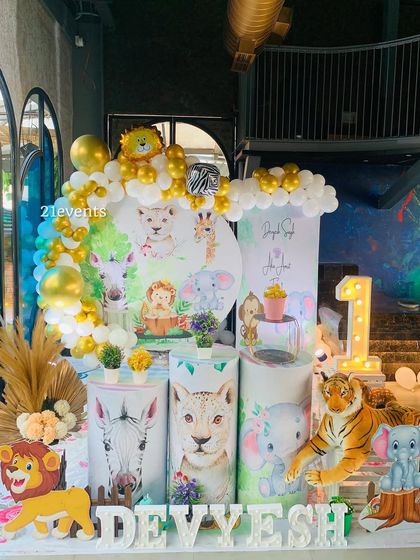 A beautiful watercolor-style jungle theme. The softer illustrations on the backdrop and pedestals give it a unique, artistic feel, complemented by gold and white balloons.