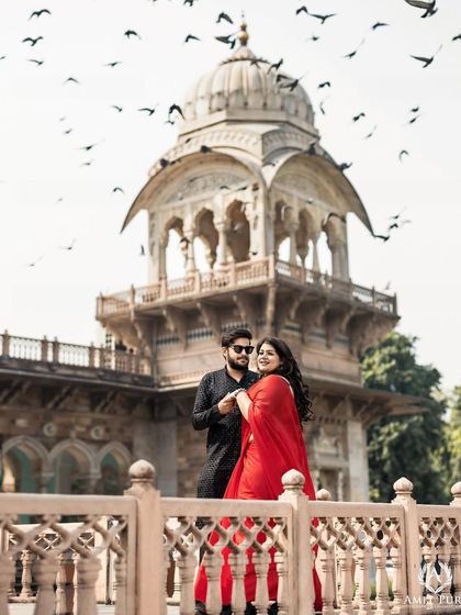 A vibrant and joyful shot in Jaipur. The bride's bright red saree pops against the classic architecture, while the birds in flight add a sense of life and movement to this beautiful pre-wedding photograph.