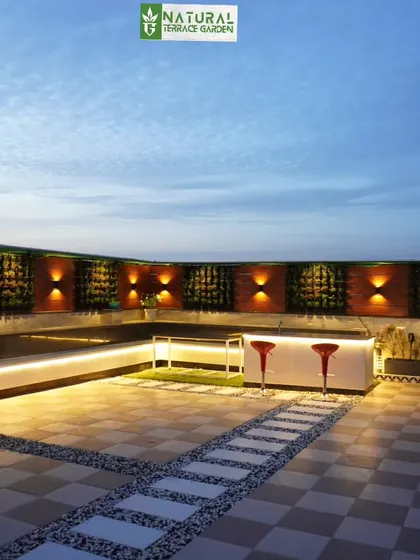 A long, modern bar with integrated bench seating and LED lighting, designed for a large rooftop in Palam Vihar.