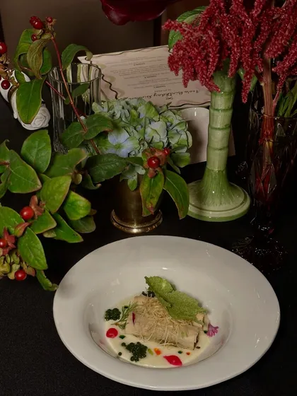 An exquisitely plated dish from one of our sit-down dinners, set against a backdrop of lush floral arrangements. We believe presentation is just as important as flavour.