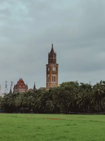 A wider view of the Rajabai Clock Tower, seen from the Oval Maidan. The contrast of the green grass and the historic stone building is beautiful.