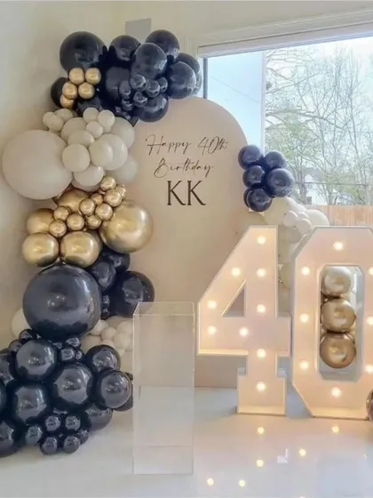 A chic 40th birthday party by the pool. The setup includes a large light-up number '40' and a stylish balloon arrangement in black, white, and gold.
