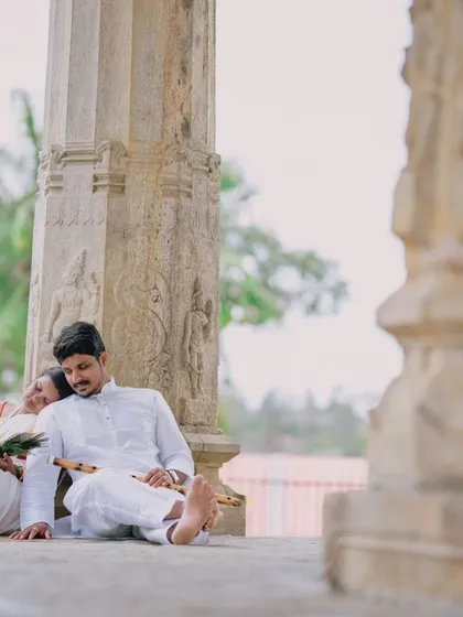 A peaceful moment of rest during a temple photoshoot. The couple's traditional white outfits create a serene and classic look against the stone architecture.