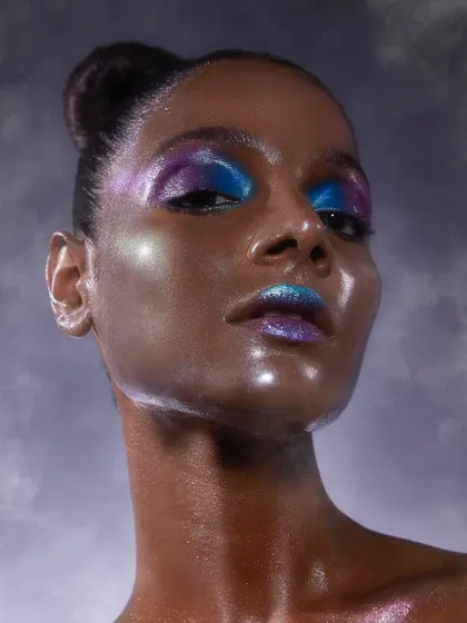 A futuristic glass skin look with a duo-chrome blend of blue and purple on the eyes and lips. This shows the high level of creativity our students achieve.
