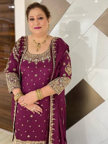 A regal and polished look for a wedding event. The makeup is kept classic with a defined eye and a soft lip, complementing her ornate purple Punjabi suit.
