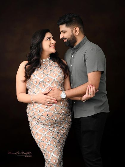 An elegant and intimate couple's portrait. The focus here is on the connection between the parents-to-be, captured with classic lighting against a rich, dark backdrop for a timeless feel.