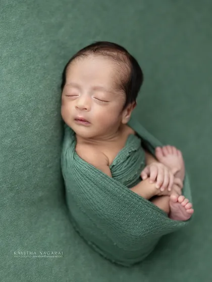 A different angle of one-week-old Aryan, showing him curled up in a womb-like pose. The green wrap provides a beautiful, natural color palette.