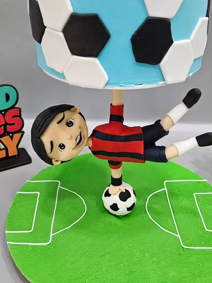 The details of our football-themed anti-gravity cake. The upside-down kicking boy is sculpted entirely from fondant and is the core of the structure, showing how figurines can be both decorative and functional.