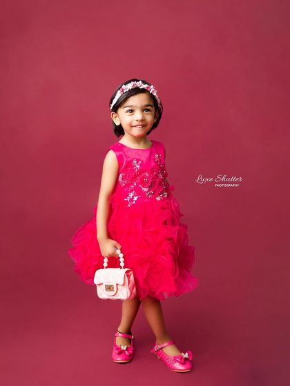 A sweet and stylish portrait of the birthday girl in her pink party dress, holding a miniature purse. Her gentle smile is absolutely precious.