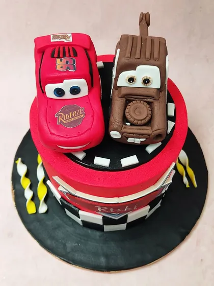 An overhead view of the Cars cake, showing the detailed fondant figures of Lightning McQueen and Mater ready to celebrate.