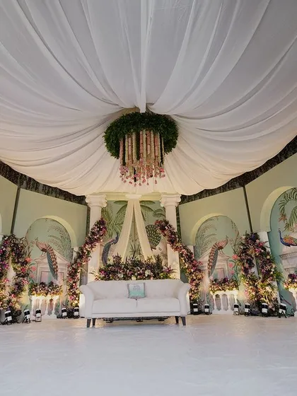 A stunning reception stage with a pastel-painted backdrop of peacocks and florals, blending artistry with natural beauty.