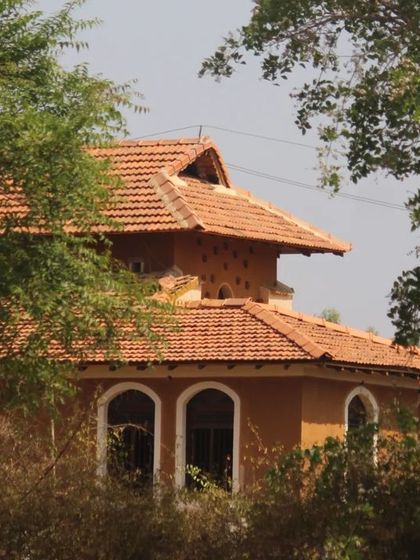 A view of the Doddaballapura mud house nestled among the trees. The sloping tiled roof and earthy walls are hallmarks of the sustainable, vernacular architecture we specialize in.