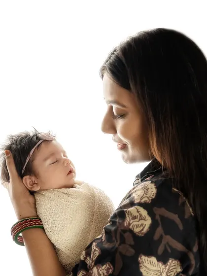 The pure joy and wonder in a mother's eyes as she holds her sleeping baby. This profile shot is intimate and full of emotion, a perfect keepsake of the motherhood journey.