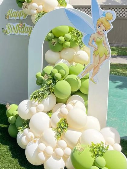 A charming Tinkerbell-themed party in a garden. I created a balloon cascade in shades of green and white flowing from a white arch backdrop, with a Tinkerbell cutout adding a touch of fairy magic.
