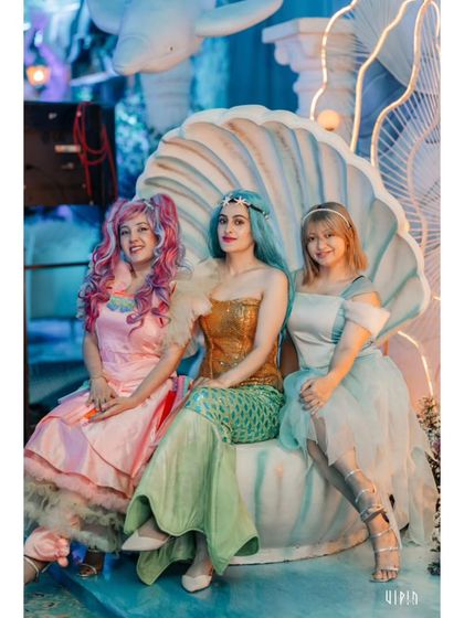 Performers dressed as beautiful mermaids pose in a giant seashell chair. Live characters are one of my favorite ways to make a theme feel real and interactive for guests.