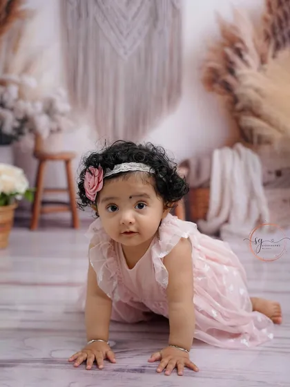 A sweet crawling pose in a delicate pink dress, this shot captures the innocence and charm of a baby girl during her first birthday session.