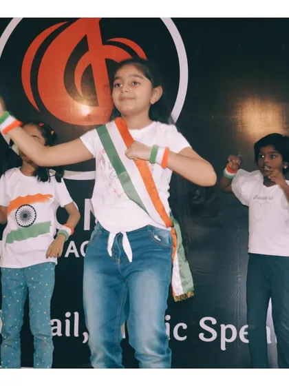 A young performer proudly wearing a tricolor sash during a patriotic dance event at our academy.