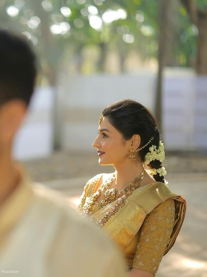 A beautiful over-the-shoulder shot of the South Indian bride. It gives a lovely view of her traditional braided hairstyle adorned with fresh flowers.