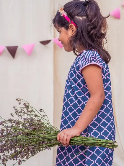 A candid shot of a girl in a modern printed dress, holding a bouquet of wildflowers. It’s a beautiful, natural moment that captures the spirit of my brand.