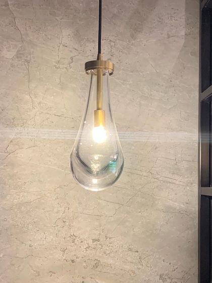 A single teardrop-shaped glass pendant light, a simple and elegant lighting solution.