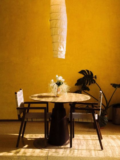 A minimalist dining set under a paper lantern, where shadows and light create a peaceful, almost zen-like ambiance.