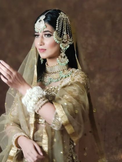 A model in a golden lehenga and mint-green jewellery, showcasing a soft and elegant look.