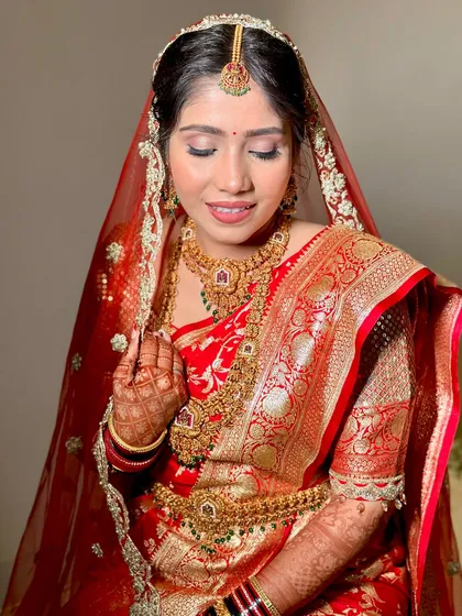 A close-up of a beautiful South Indian bride. The makeup is kept classic and radiant to complement her traditional red and gold silk saree.