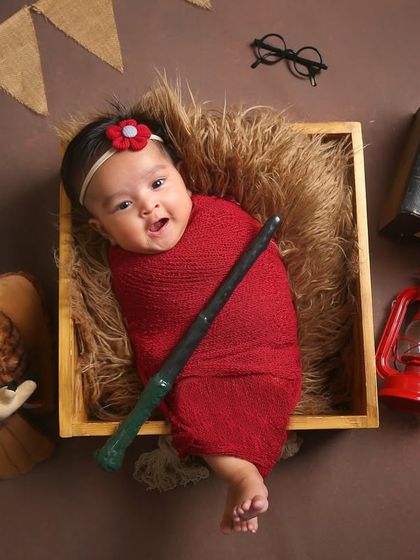 Our little witch is ready for Hogwarts. This Harry Potter setup includes a wand, books, a lantern, and an owl, creating a magical world for this alert newborn.