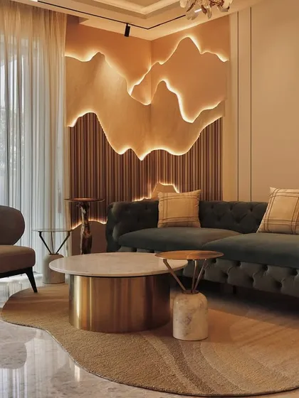 This living space is defined by a custom-designed, back-lit wall feature with organic, flowing lines. We paired this dramatic element with a classic tufted sofa, a modern armchair, and a nested coffee table in brass and marble to create a room that is both sophisticated and inviting.