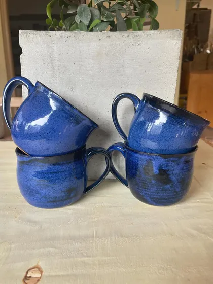 A collection of my handmade ceramic mugs, each with its own unique shape and glaze. The little coffee bean detail on the handle is a fun touch for coffee lovers.